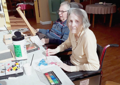 Two residents at Princess Christian painting in the conservatory