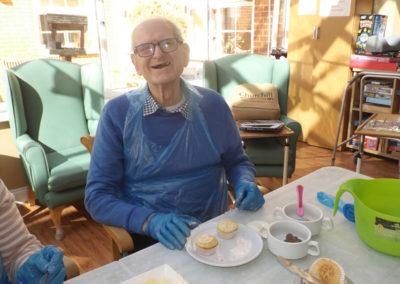 Princess Christian Care Home resident decorating some cupcakes with icing and toppings