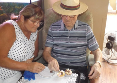 Two residents enjoying decorating a cake