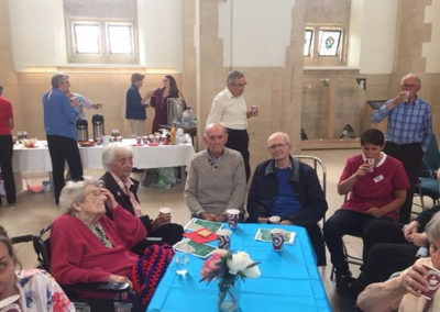 A group of residents around a table enjoying tea and cake inside Guildford Cathedral