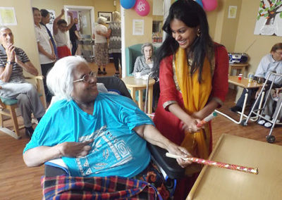 Female resident at Princess Christian in her wheelchair tapping an instrument along to Bollywood music