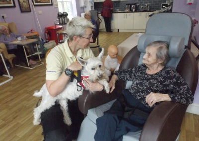 Female resident enjoying stroking Pet Therapy dog Billy at Princess Christian