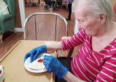 Female resident at Princess Christian applying tomato sauce to a plain pizza base