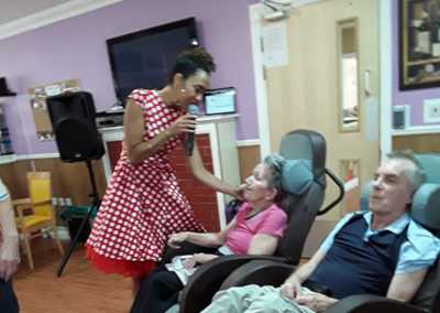A singer performing for two seated residents