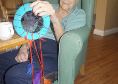 A seated lady resident making a dream catcher