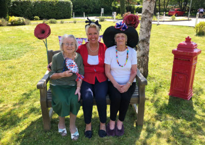 Two Princess Christian Care Home residents and Hairdresser Elaine enjoying the sunny front garden on VE Day 2020