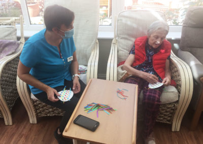 Princess Christian Care Home resident and staff member making carnival decorations together